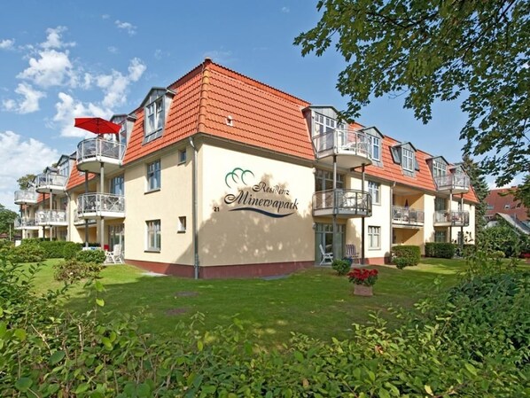 A multi-story residential building with balconies, a garden, and a clear sky. - Minervapark Whg. Mi13 (Ostseebad Boltenhagen)