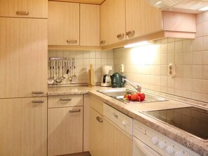 A kitchen with wooden cabinets, a countertop, a sink, and a stove. - Minervapark Whg. Mi13 (Ostseebad Boltenhagen)