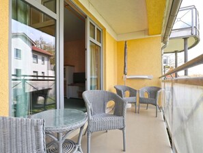 Ein Balkon im Freien mit Korbmöbeln und einem Glastisch mit Blick auf eine Wohngegend.