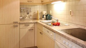 A kitchen with wooden cabinets, a countertop, a sink, and a stove. - Minervapark Whg. Mi13 (Ostseebad Boltenhagen)