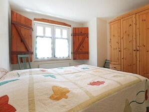 A bedroom with a bed, a window, wooden cabinets, and a radiator. - Minervapark Whg. Mi13 (Ostseebad Boltenhagen)
