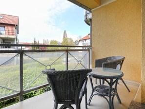 A balcony with wicker furniture and a view of a green landscape.