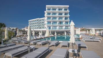 A hotel with multiple floors, a swimming pool, and numerous sun loungers.