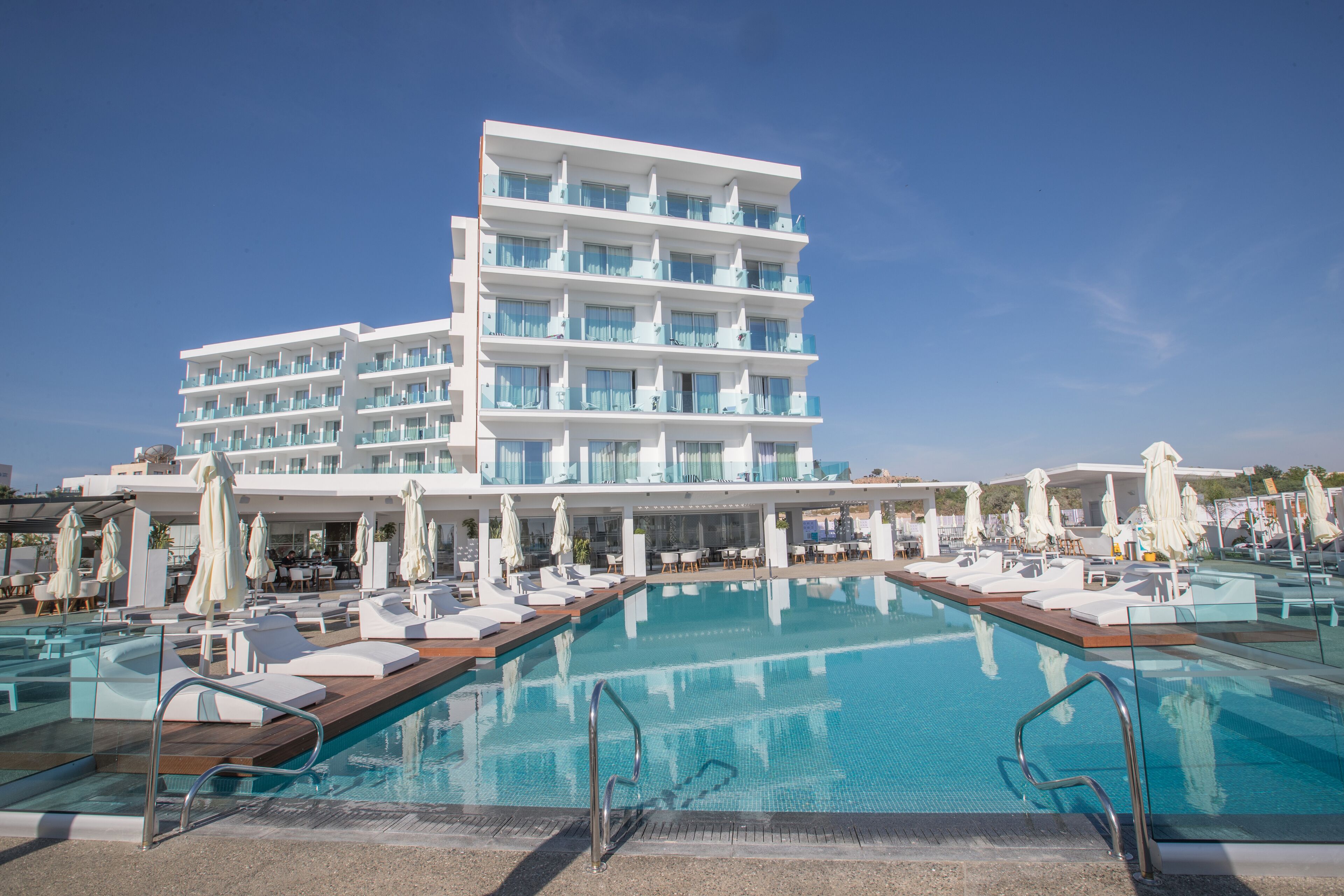A hotel with a large pool area, multiple balconies, and outdoor seating.