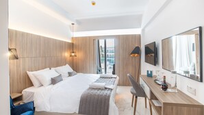 A modern hotel room with a large bed, a desk, and a city view through the window. - The Blue Ivy Hotel and Suites (Paralimni)