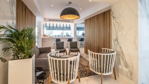 A modern lobby with a seating area, a large plant, and a view into the dining area. - The Blue Ivy Hotel and Suites (Paralimni)
