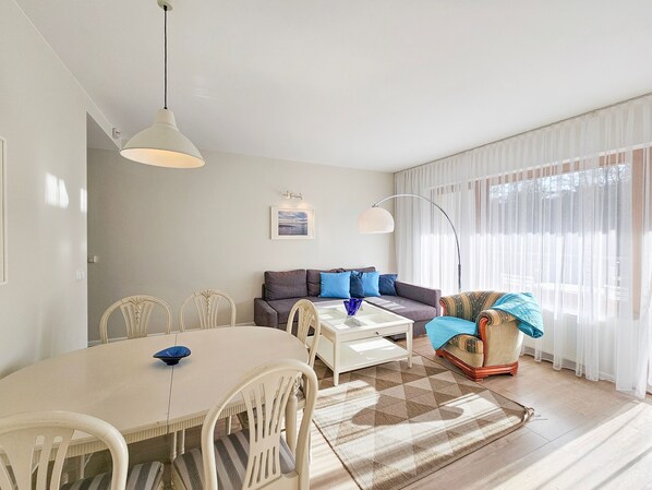 A well-lit living room with a dining area, a sofa, and a patterned rug.