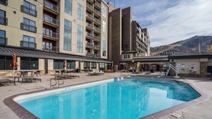 Piscina rodeada de mobiliario exterior y un edificio con varios balcones.