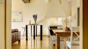 A modern kitchen with a dining area, a sofa, and a table with a vase of flowers. - Spacious apartment in the centre of the old town near cafes, beach, and more (Nice)