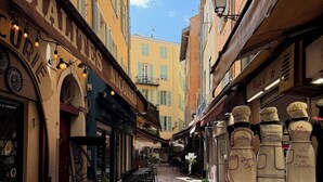 A narrow street with hexagonal tiled flooring, cafes, and shops with visible signage. - Spacious apartment in the centre of the old town near cafes, beach, and more (Nice)
