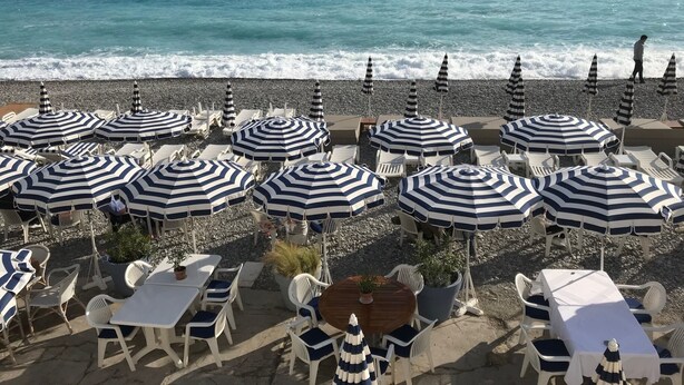 A beachside restaurant with outdoor seating, including tables and chairs, and striped umbrellas. - Spacious apartment in the centre of the old town near cafes, beach, and more (Nice)