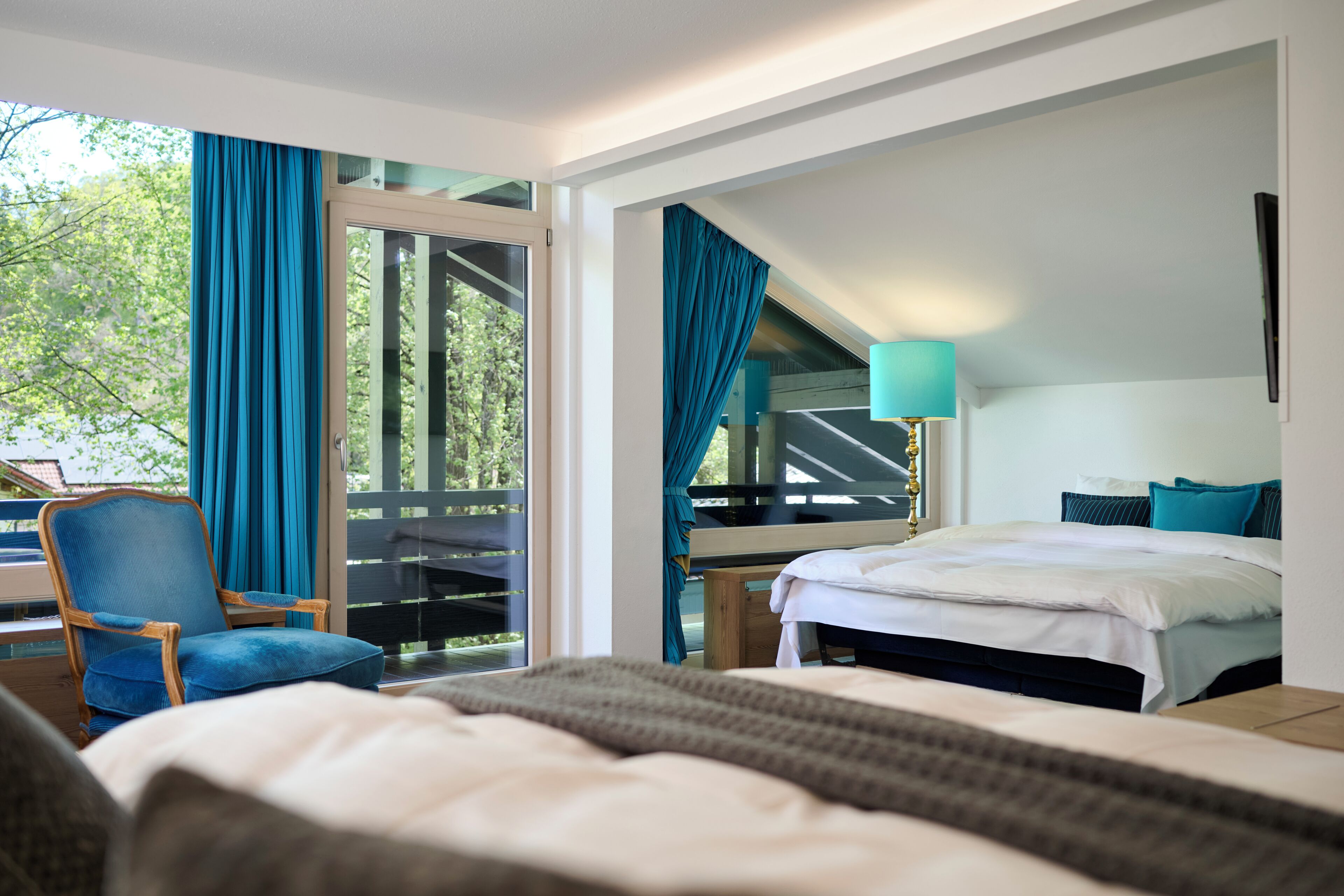 A hotel room with a bed, a chair, a desk, and a view of the outdoors.