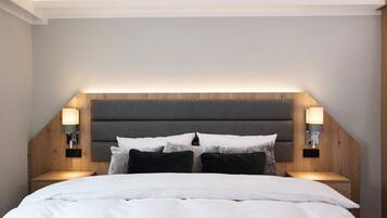 A bedroom with a bed, headboard, bedside tables, and wall-mounted lighting.