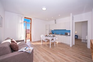A modern living room with a sofa and a dining area with a table and chairs. - Residenza Giada (Riva del Garda)