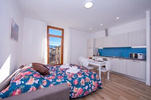A compact bedroom with a bed, a desk, and a kitchenette. - Residenza Giada (Riva del Garda)