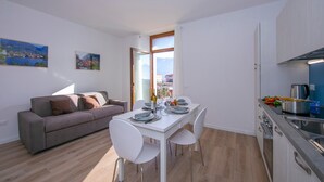 A modern apartment with a dining area, kitchenette, and a sofa. - Residenza Giada (Riva del Garda)