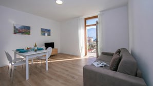 A modern living room with a dining area, a sofa, and a TV. - Residenza Giada (Riva del Garda)