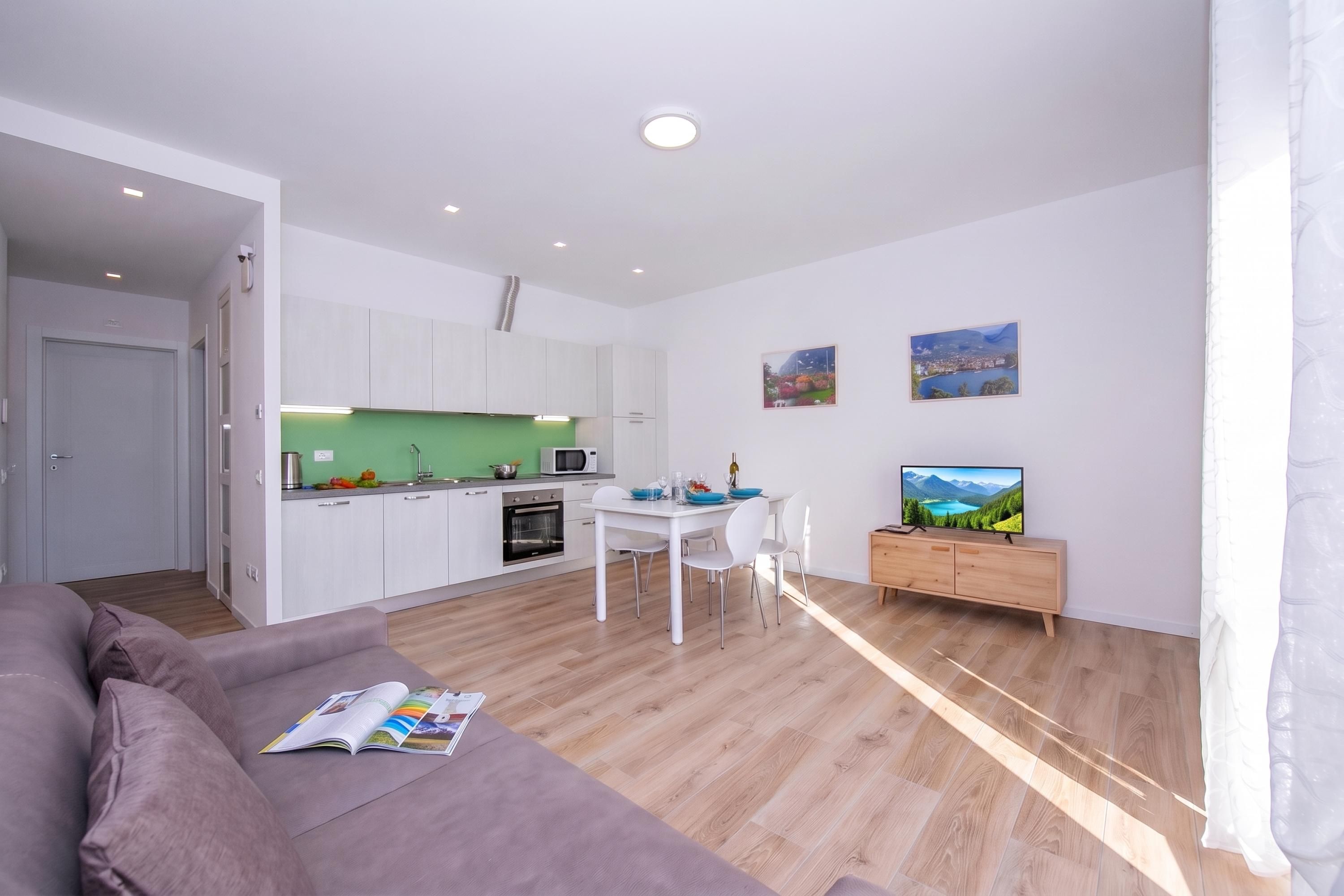 Een moderne woonruimte met keuken, eethoek en een bank.