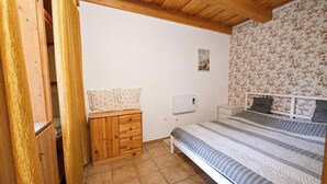 Un dormitorio con un armario de madera, una cama con colcha a rayas y un papel tapiz floral en una pared.