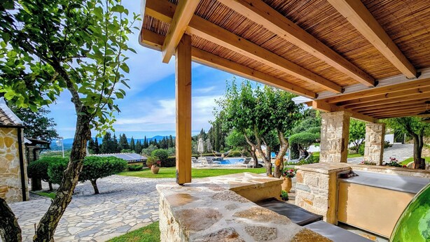 A covered outdoor area with stone flooring, a pool, and a stone structure with a grill. - Serenity Villa Retreat in Corfu Close to Resort (Corfu)