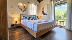 Ein geräumiges Schlafzimmer mit einem großen Bett, einem hölzernen Kopfteil und Blick ins Freie durch eine Schiebetür.