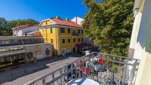 A yellow building with a red roof, a street with a metal railing, and a parked scooter. - Apartments Villa Katarina (Selce)