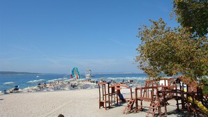 A beach with umbrellas, chairs, and a lifeguard tower. - Apartments Villa Katarina (Selce)