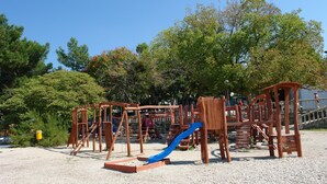 A playground with wooden structures and a blue slide. - Apartments Villa Katarina (Selce)