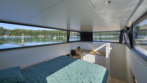 Ein kleines Zimmer mit Bett, Schreibtisch und Seeblick mit Booten.