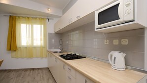 A modern kitchen with a microwave, kettle, and gas stove. - Apartment Masholina (Tribunj)