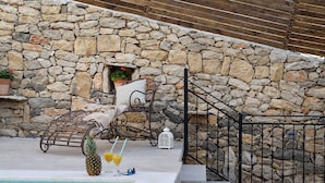 A stone wall, a pool, and a lounge area with a pineapple and drinks. - Villa Calandra (Vrana)