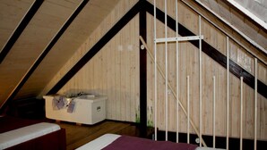 A bedroom with a sloped ceiling, wooden walls, a white bed, and a white chest of drawers. - Apartments Cukarin (Bol)