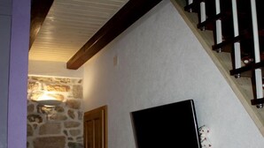 A hallway with a stone wall, a wooden door, and a black framed object on the wall. - Apartments Cukarin (Bol)