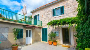 A stone building with a balcony, potted plants, and a door. - Apartments Cukarin (Bol)