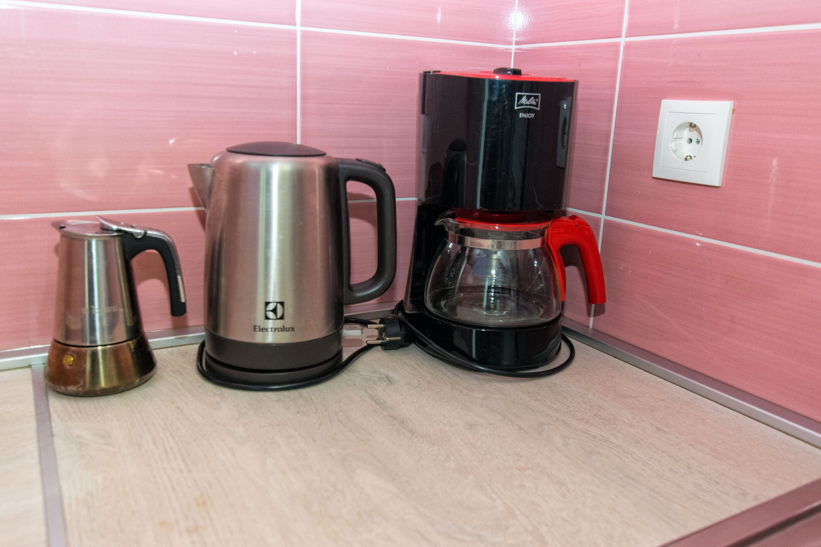 A kitchen with a coffee maker, a kettle, and a glass carafe on a countertop.