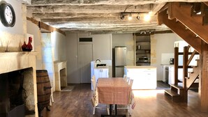 A rustic kitchen with a wooden table set for dining, a fireplace, and a clock on the wall. - Moulin aux Ans, charming gîte in a former schoolhouse (Archignac)