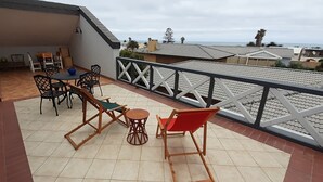 Una veranda coperta con tavolo e sedie, un piccolo tavolino rotondo e una sedia rossa.