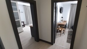 Una camera d'albergo con pavimento in legno, una scrivania con una sedia, una TV montata a parete e un piccolo tavolo con una sedia.