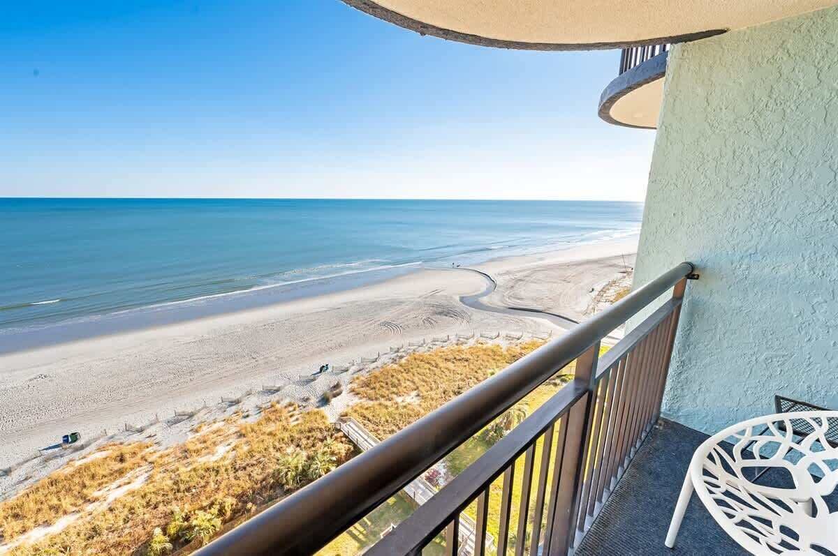 A balcony with a view of a beach and ocean.