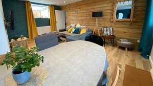 A modern living room with a sofa, a dining table, and a potted plant.
