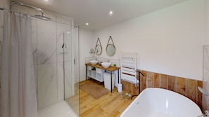 Un bagno moderno con cabina doccia in vetro, una vasca da bagno freestanding e un mobile vanitario con due lavabi.