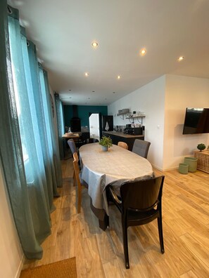 Un espace repas moderne avec une table ronde, des chaises et une cuisine en arrière-plan.