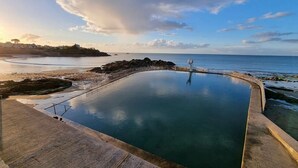 A swimming pool with a wooden deck and a view of the ocean.