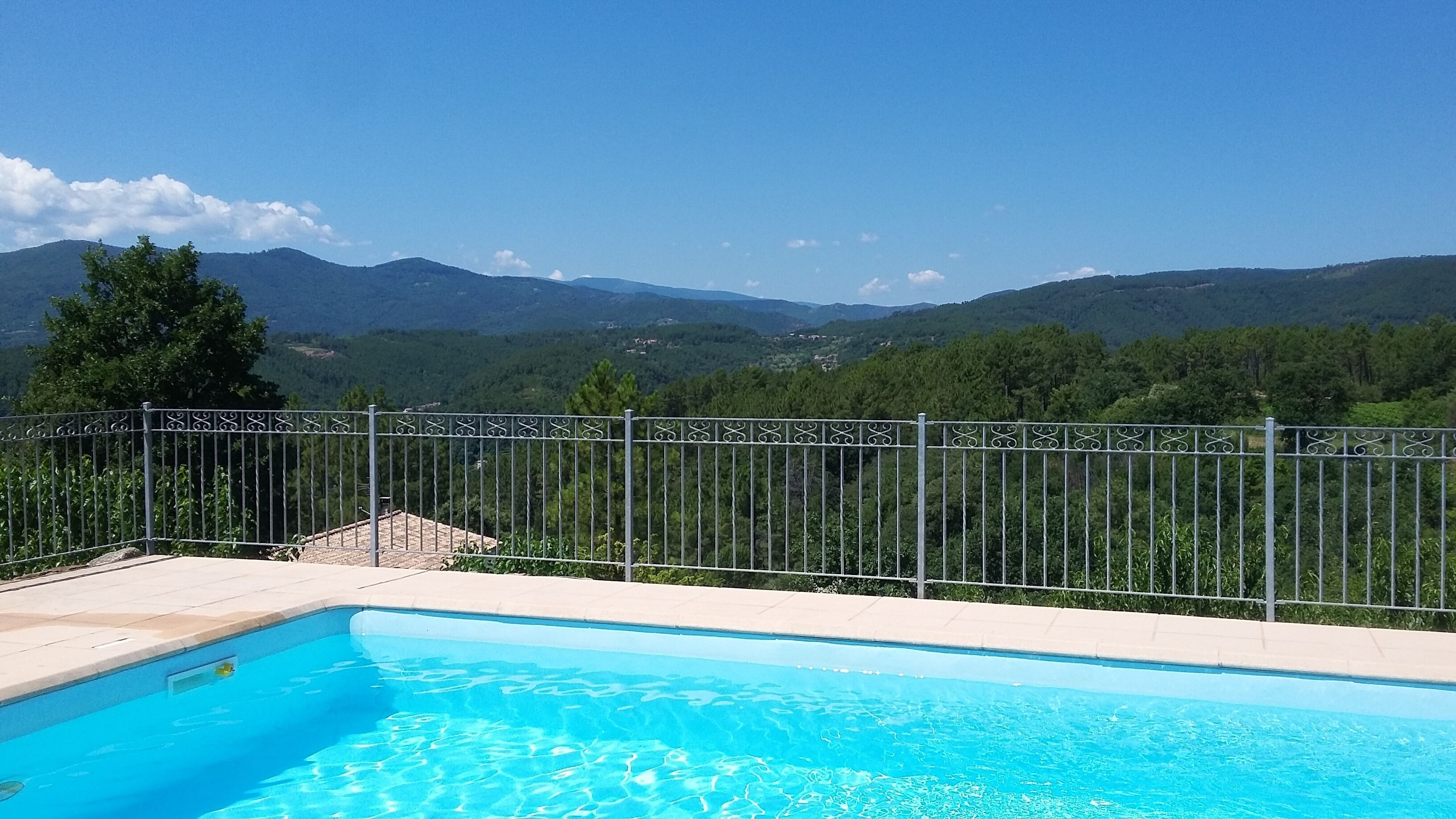A swimming pool with a view of mountains and a metal fence.