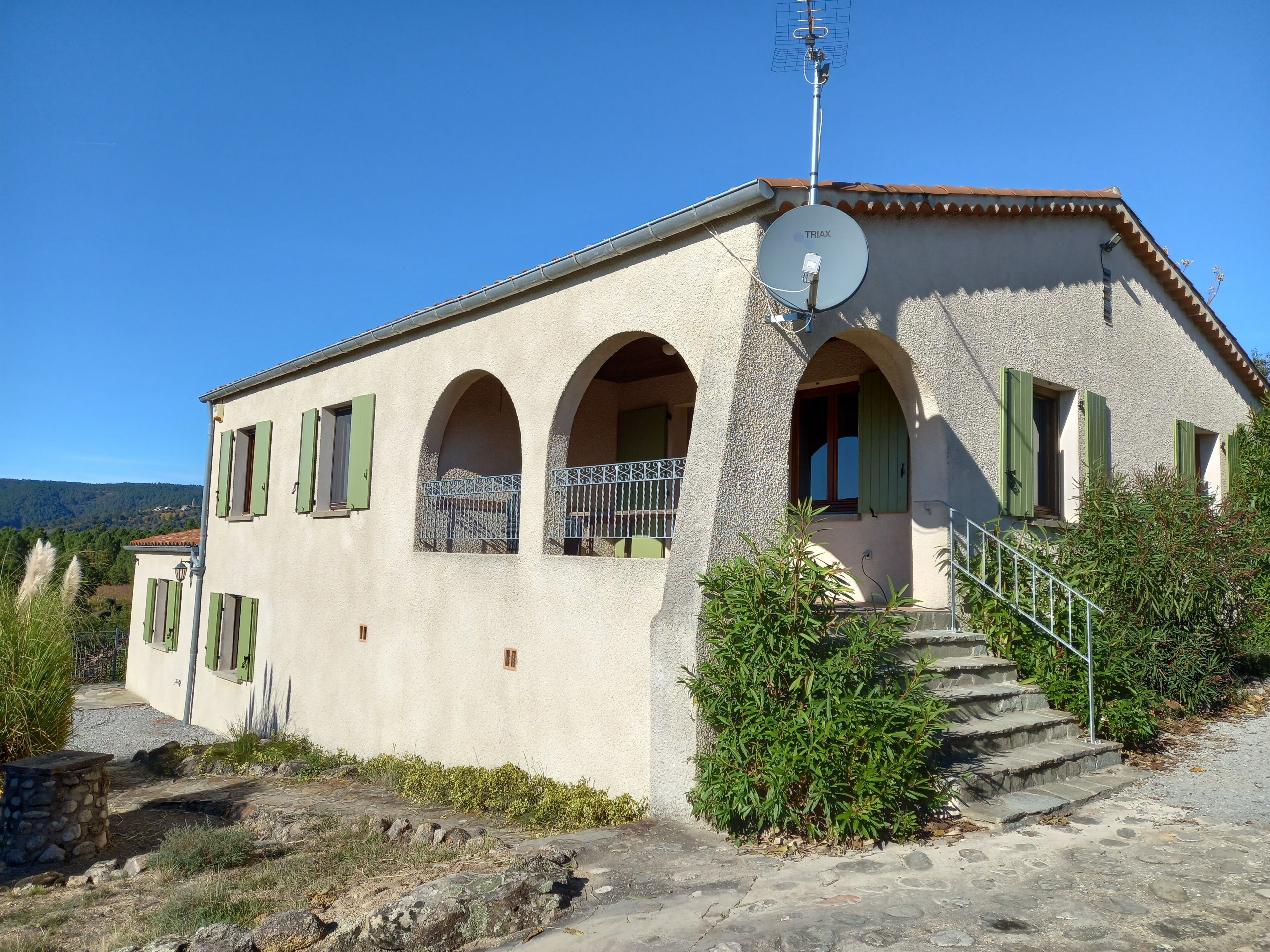 A building with a satellite dish, arched windows, and a staircase leading to the entrance.