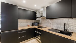 Cozinha moderna com armários escuros, painel de azulejos, micro-ondas e pia.