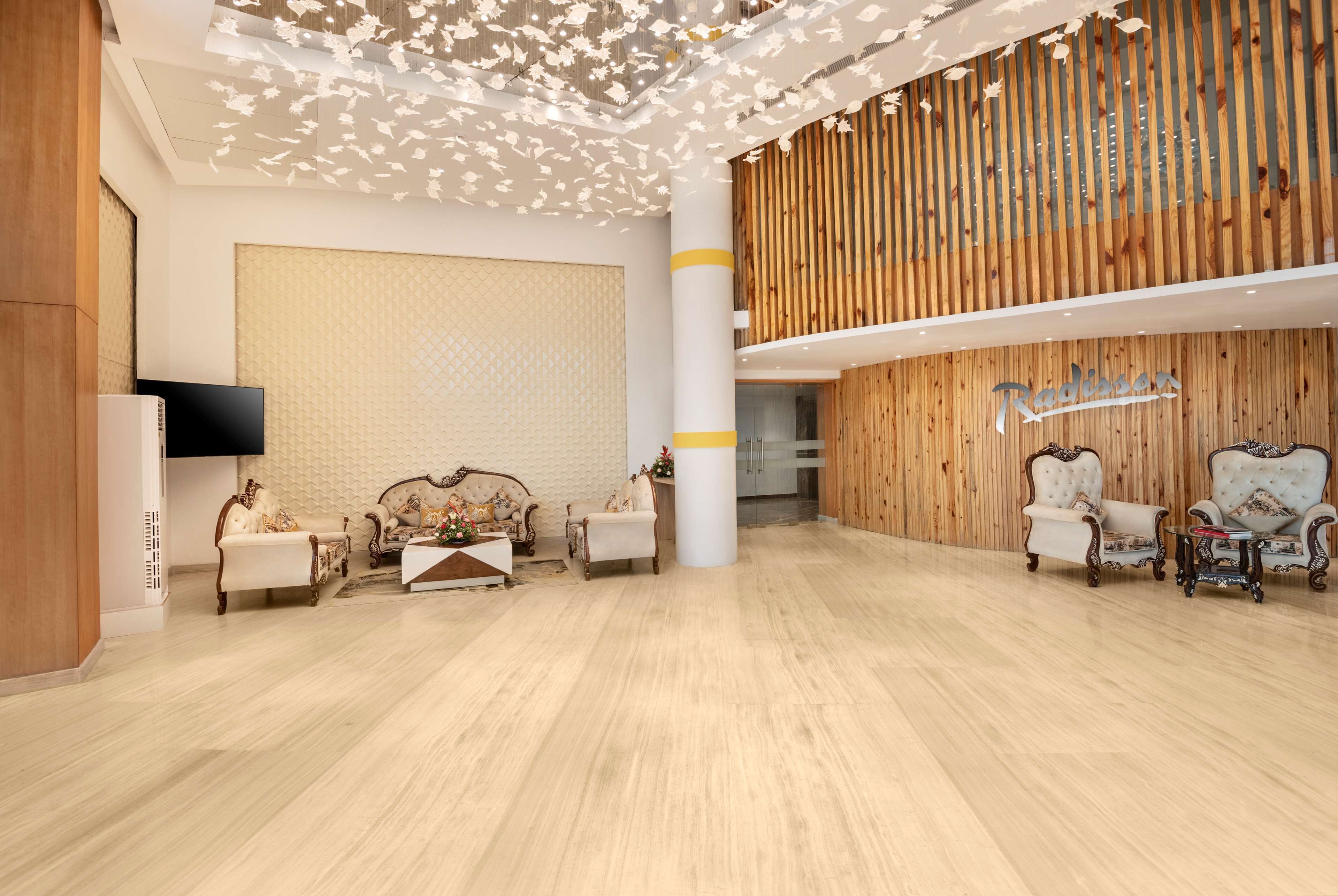 A spacious lobby with a wooden reception desk, elegant seating, and a flat-screen TV.