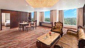 A hotel room with a dining area, a large chandelier, a sofa, and a view of the outdoors. - Radisson Hotel Bareilly Airport (Bareilly)
