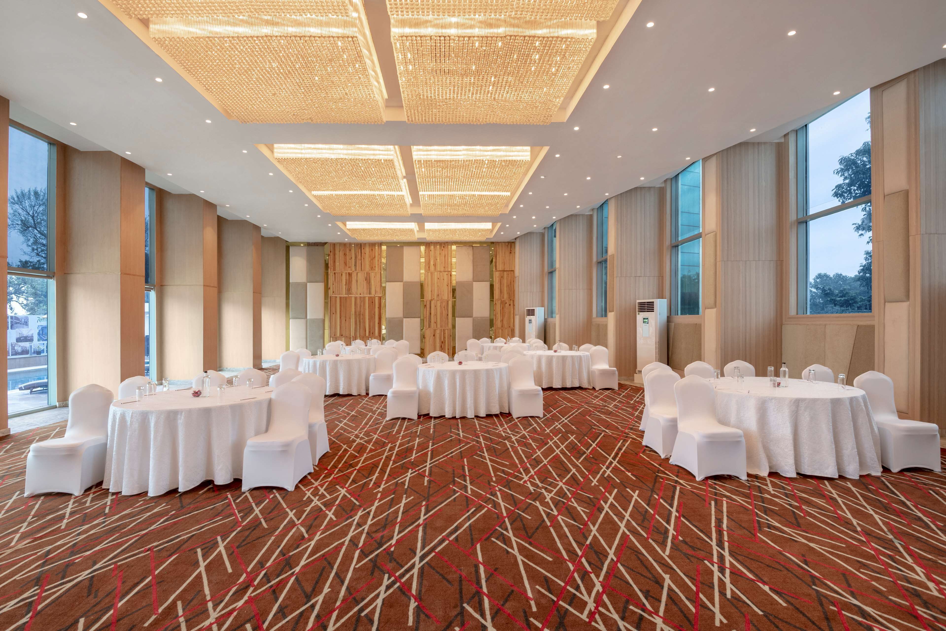A conference room with round tables, white chairs, and a patterned carpet.