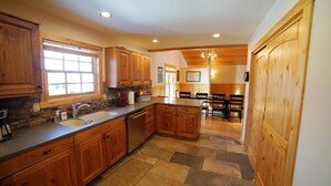 A spacious kitchen with wooden cabinets, a large island, and a dining area with a chandelier.